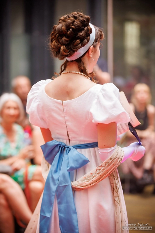 Photo de dos d'une femme en costume 1er empire avec maquillage et coiffure historique inspirée par la Reine Hortense lors d'un défilé