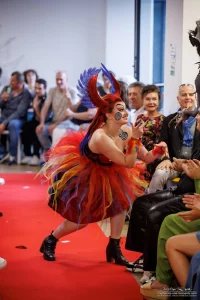 Photo d'un défilé d'un look inspiré de Iago dans Aladdin, hypnotisé, avec coiffure artistique et spirales sur le corps, et robe multicolore