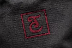 Mockup de logotype monogramme CT en broderie sur un tissu noir