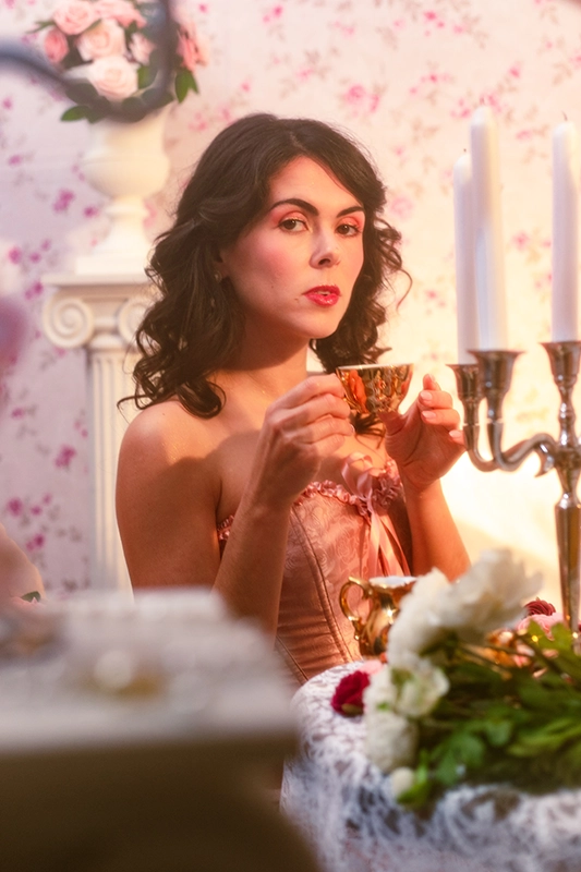 Shooting photo d'une femme avec une tasse de thé à la main et un corset dans un style baroque rococo, un décor riche et des tons roses